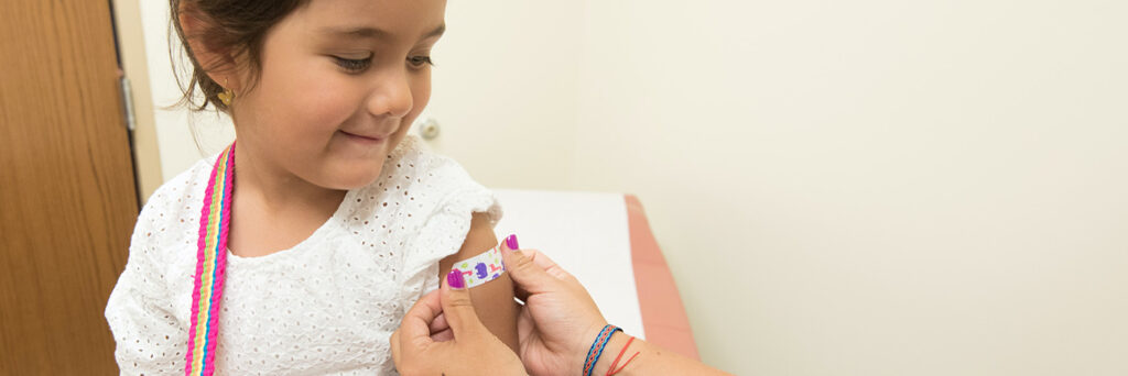 Child getting a band-aid put on their arm following a vaccine